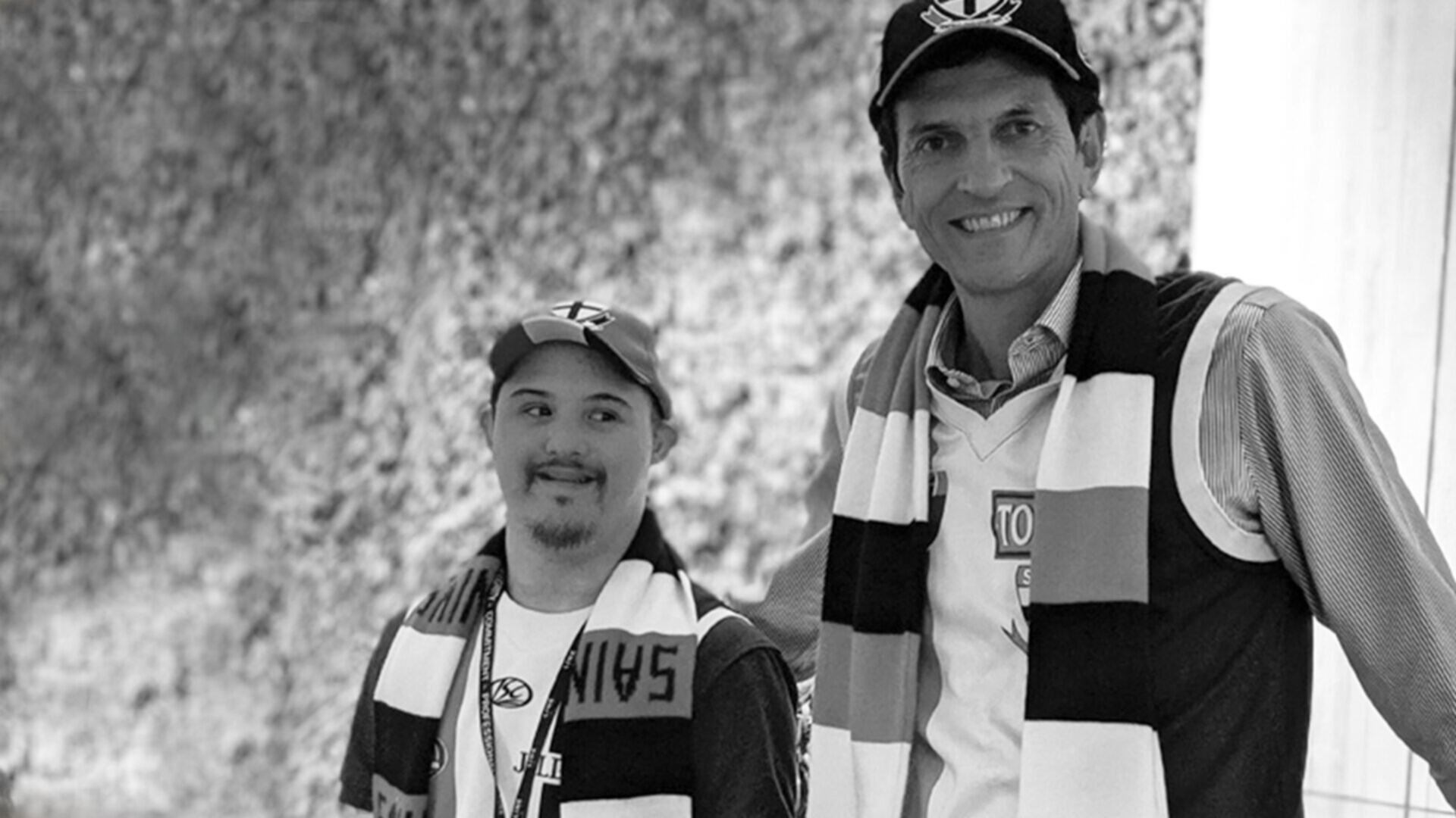 [Photo description: Lincoln is standing next to the CEO of Empirics. Both men are wearing Saint Kilda Footy Club hats, scarfs and shirts.]