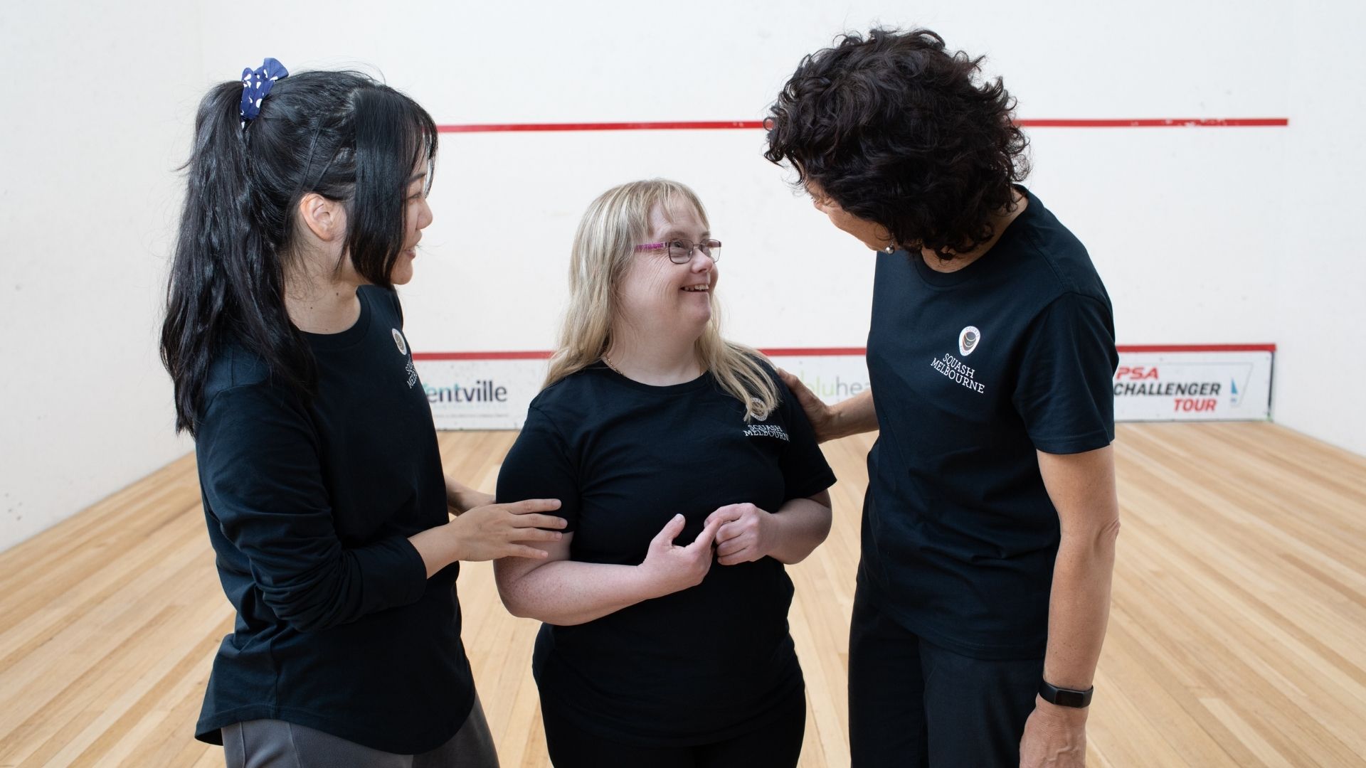 Kelly is laughing with her two employers on the courts of Squash Melbourne