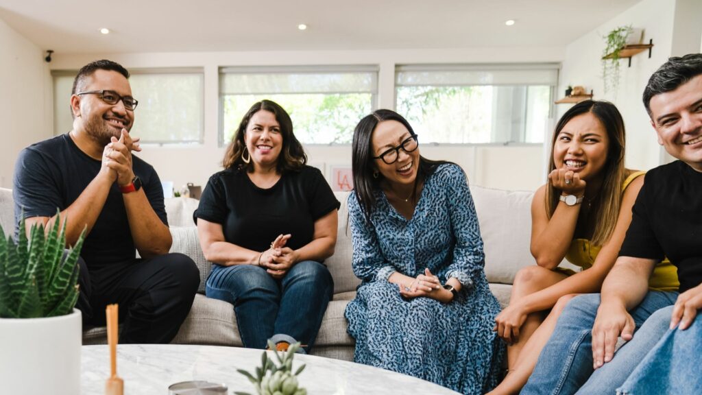 Group of smiling men and women seated on a couch.