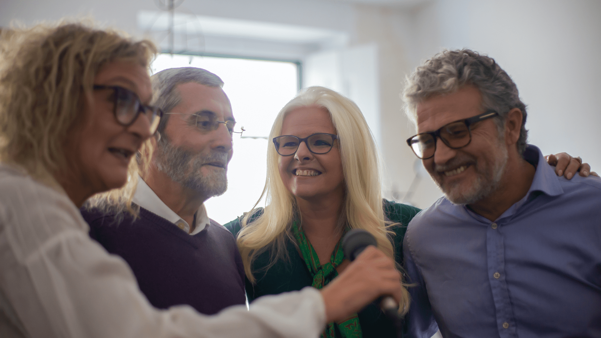 Smiling group of middle aged men and women in a supportive embrace.