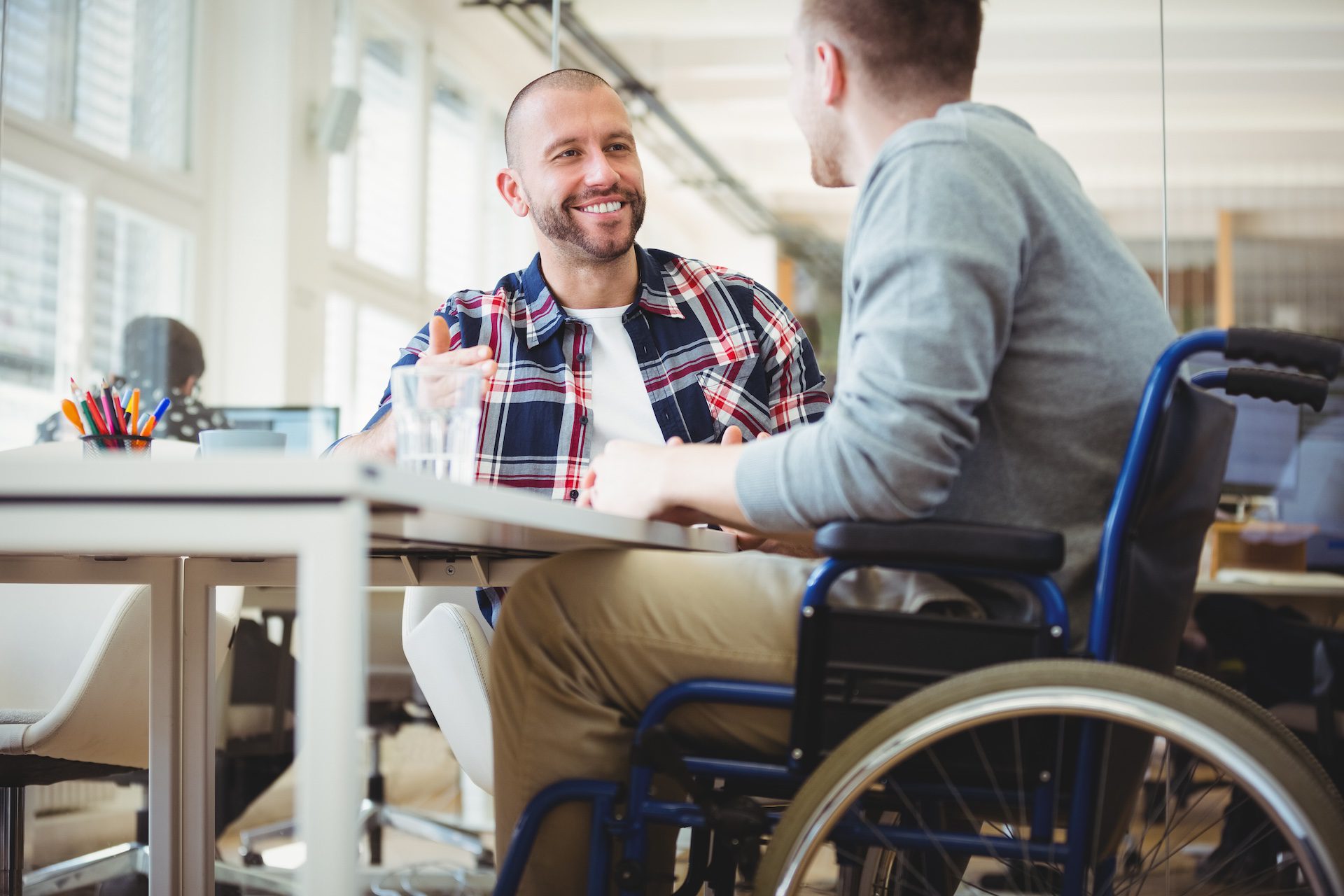 Businessman with a disability sitting with a colleague in an office.