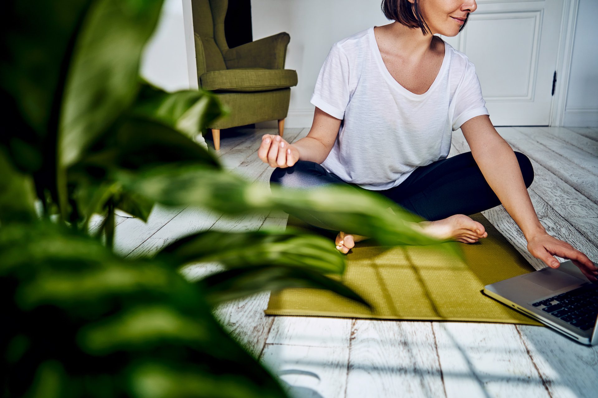Female practicing yoga at home during quarantine, celebrating National Yoga Day, using palo santo sticks for meditation.