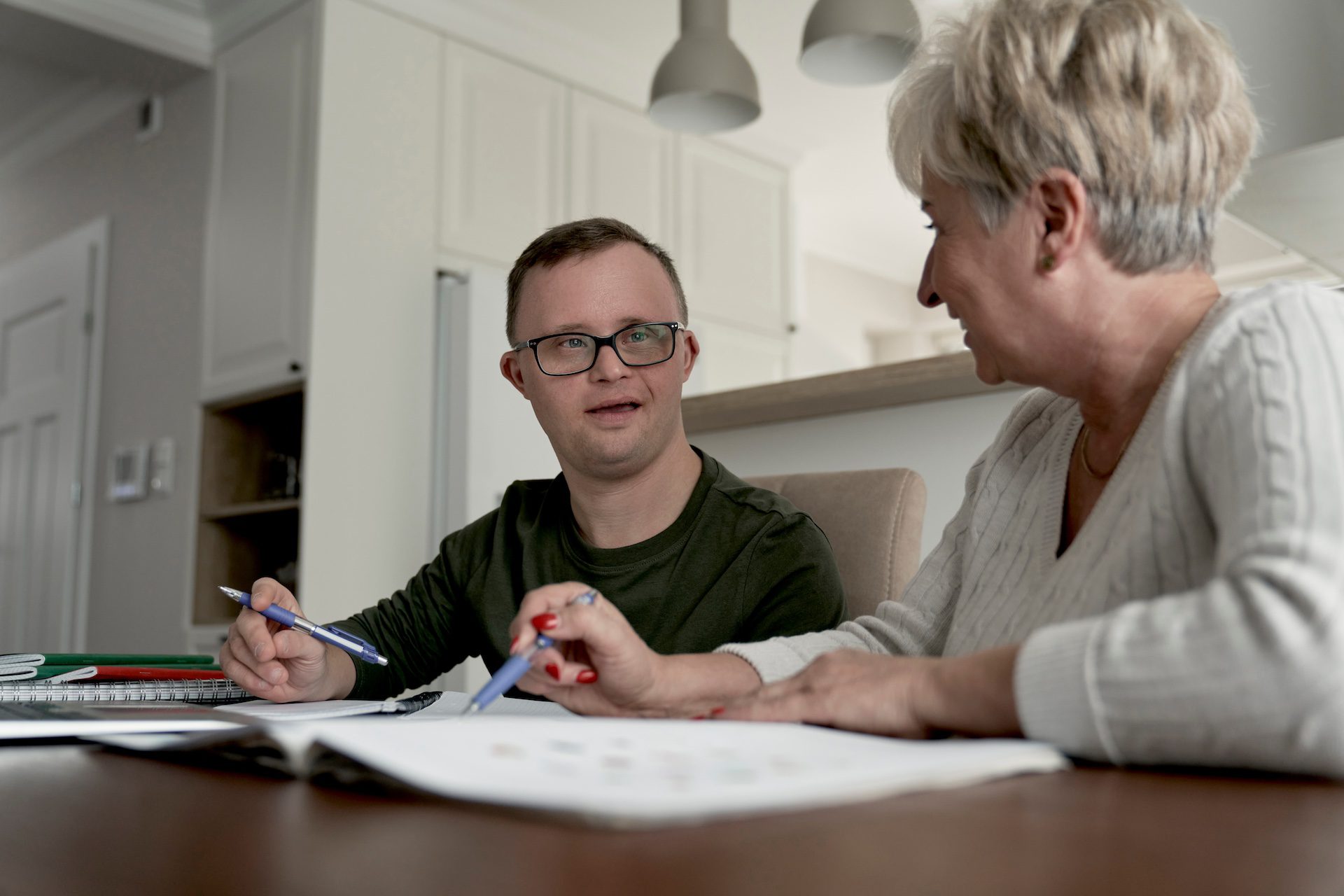 Caucasian man with down syndrome learning with his mum at home.