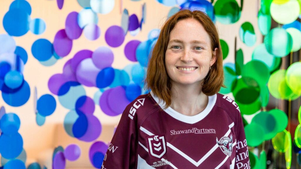 Red-haired woman smiling in front of a colorful background.