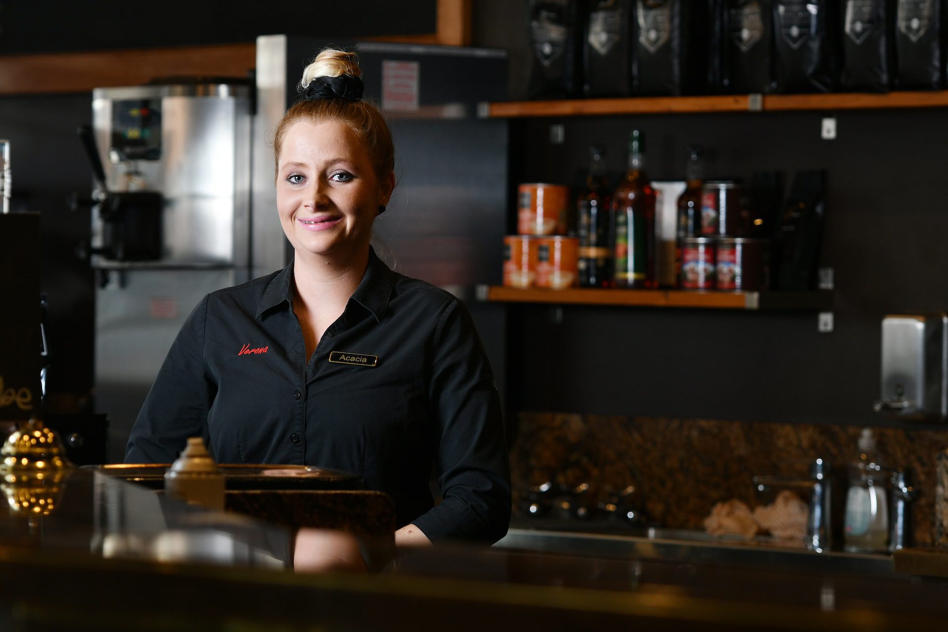 Woman smiling behind a restaurant bar counter.