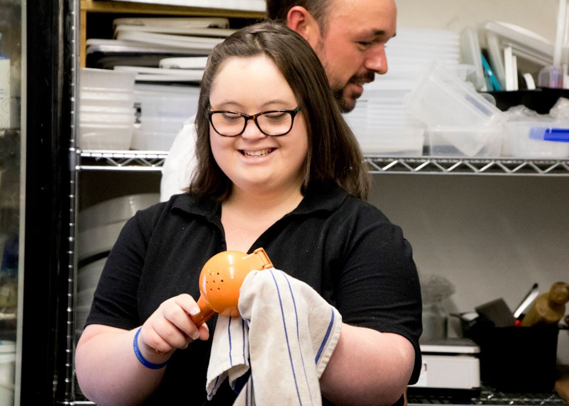 Young woman in a kitchen stock room wiping a lemon squeezer.