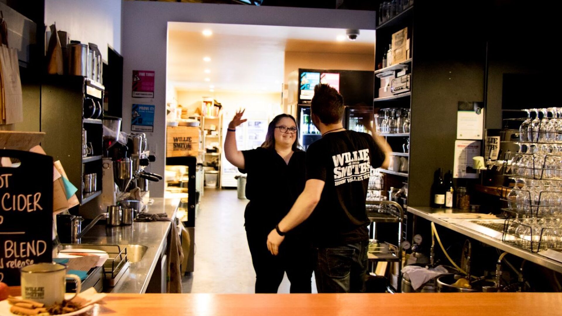 Young man and woman about to high five behind a restaurant counter.