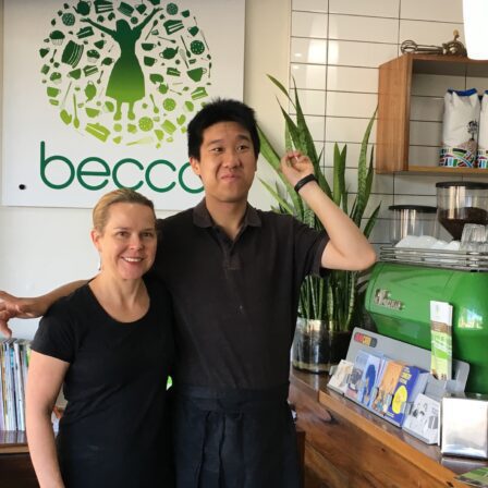 Young Asian man and middle-aged woman standing beside a cafe counter.