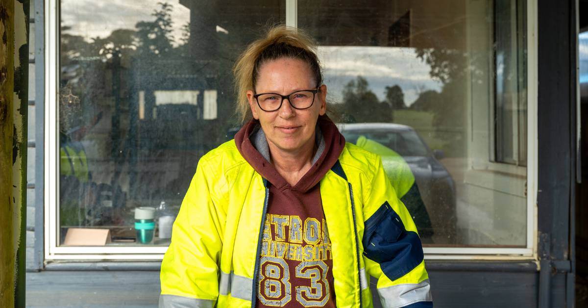 Kylie is wearing a yellow hi vis jacket, smiling at the camera