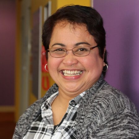 Middle-aged woman smiling widely in an office.