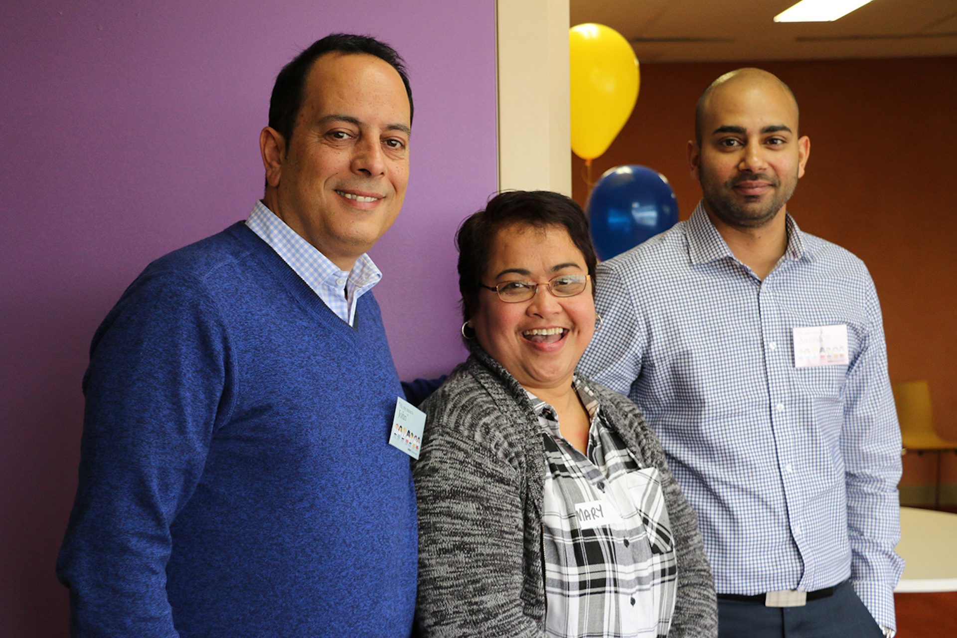 Two men and a woman celebrating in an office.