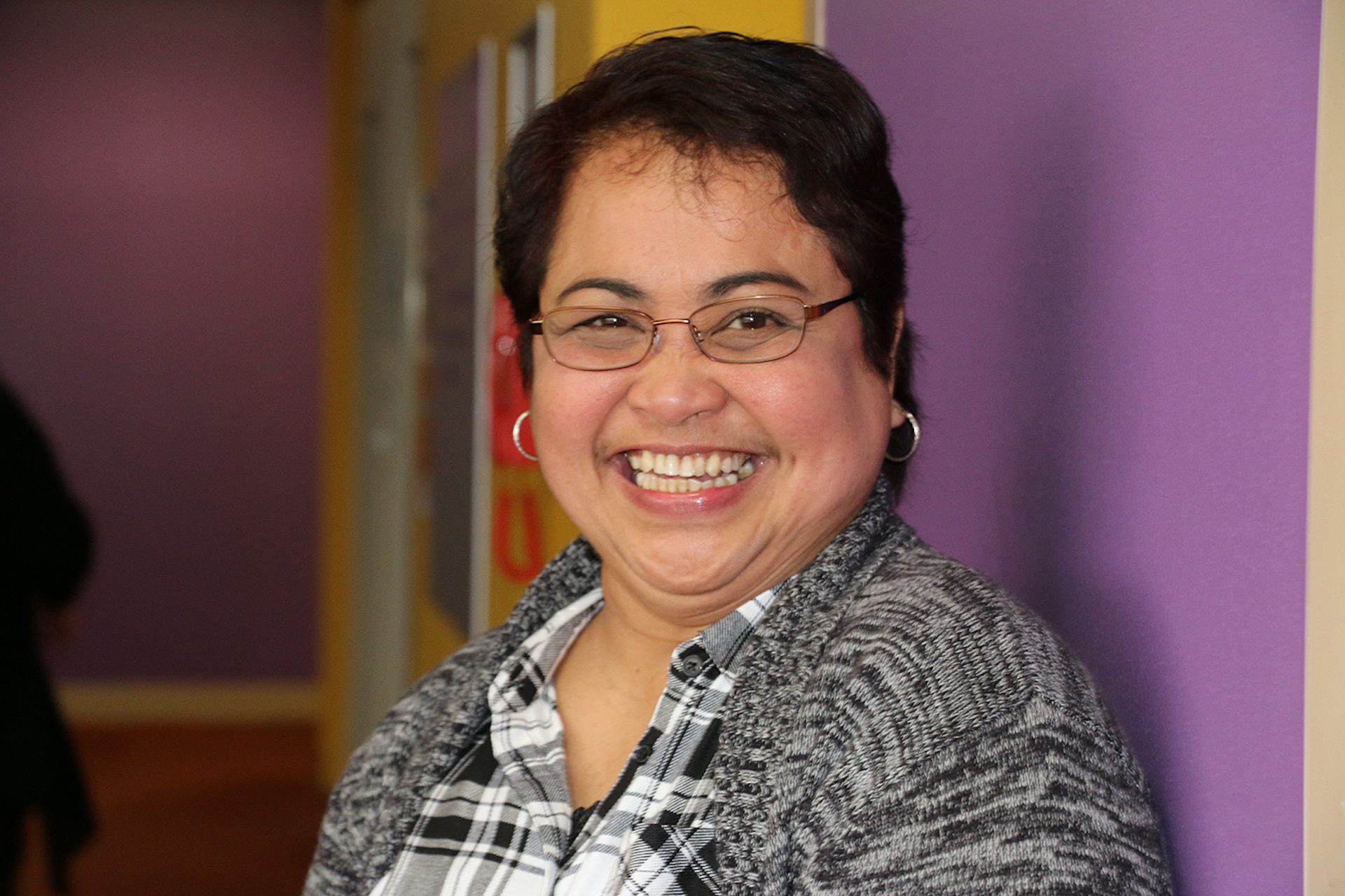Middle-aged woman smiling widely in an office.