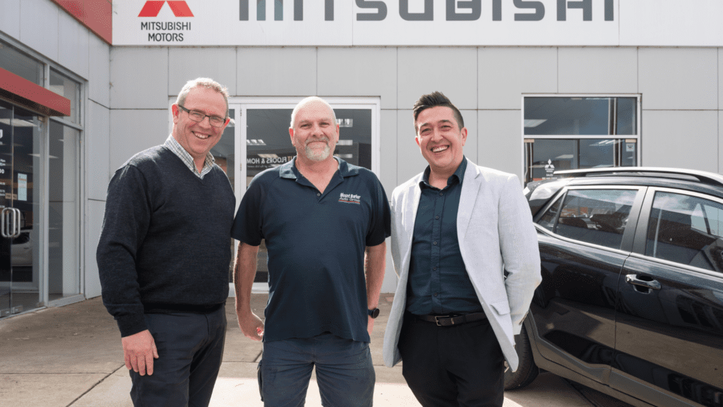 Team at Maughan Thiem pictured smiling with WISE Employment Business Manager, Horacio, next to a black car