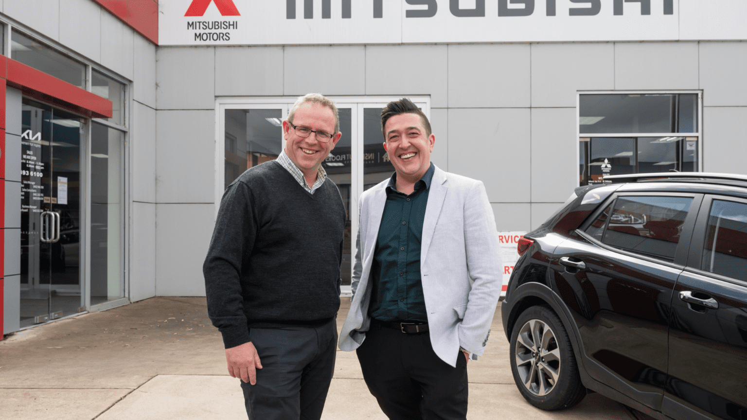 Team at Maughan Thiem pictured smiling with WISE Employment Business Manager, Horacio, next to a black car