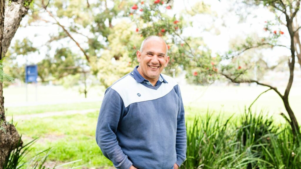 Smiling man standing in the park.