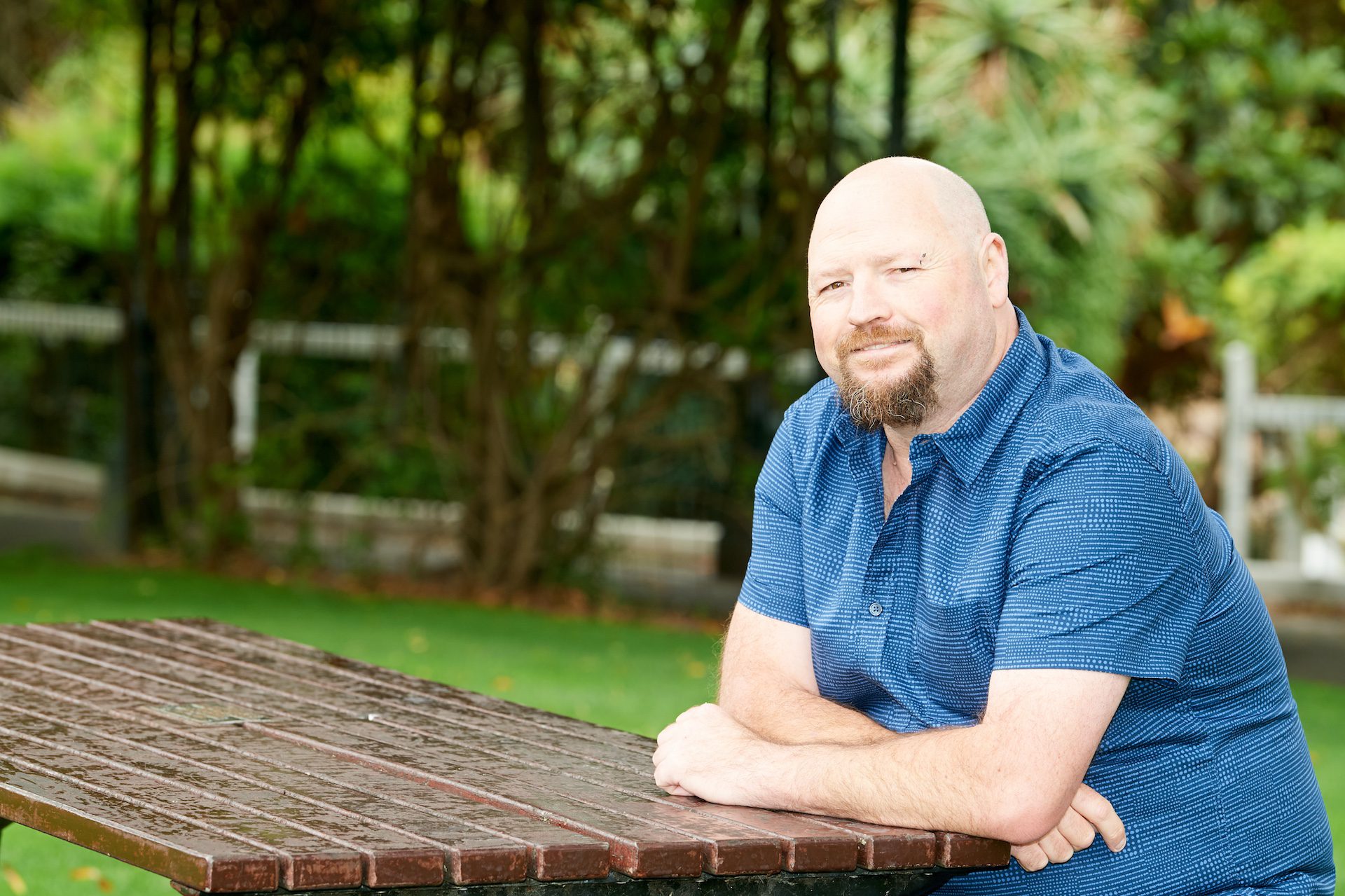 Smiling man sitting at a picnic table.