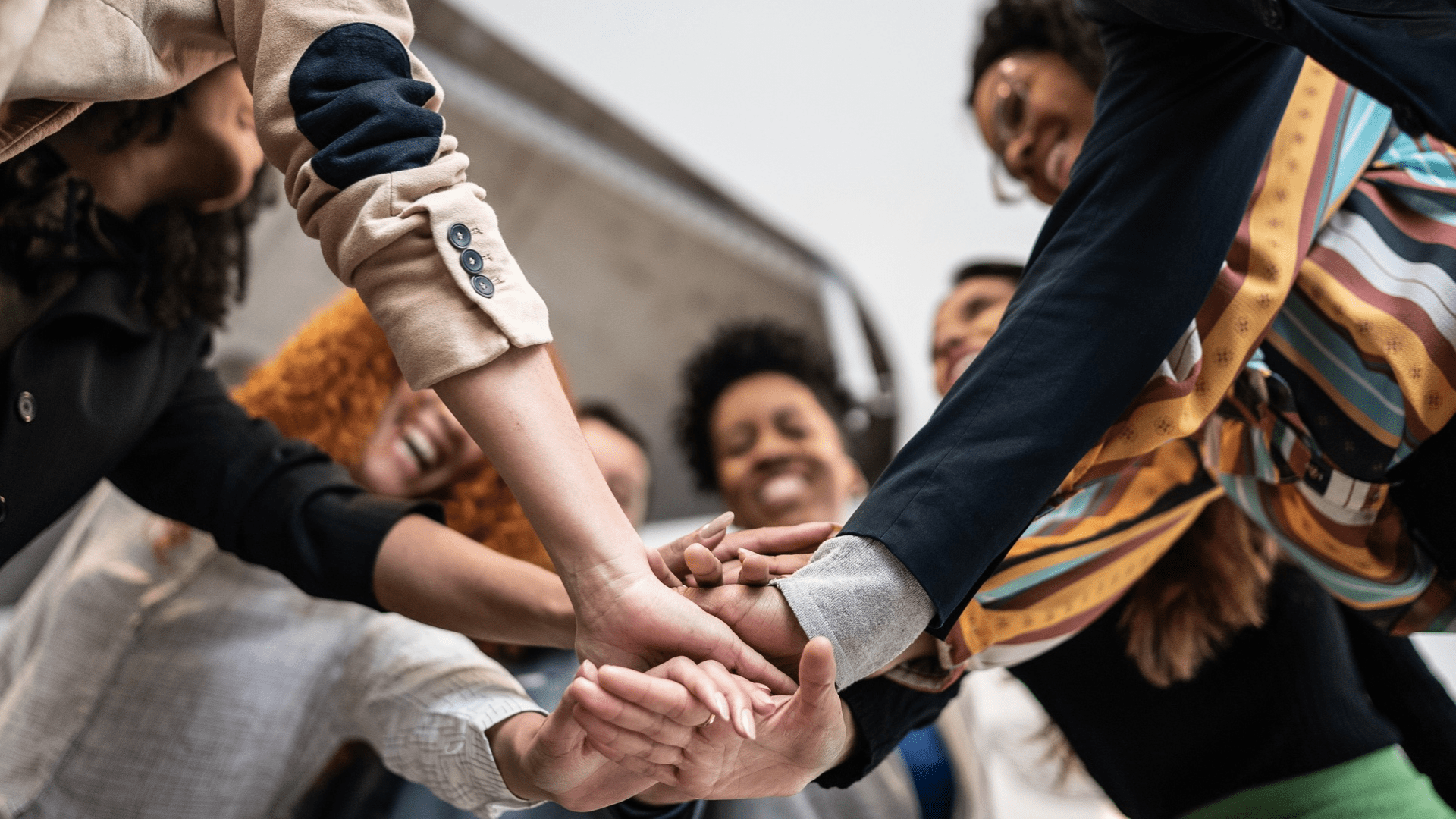 group of people putting their hands in the middle of a circle