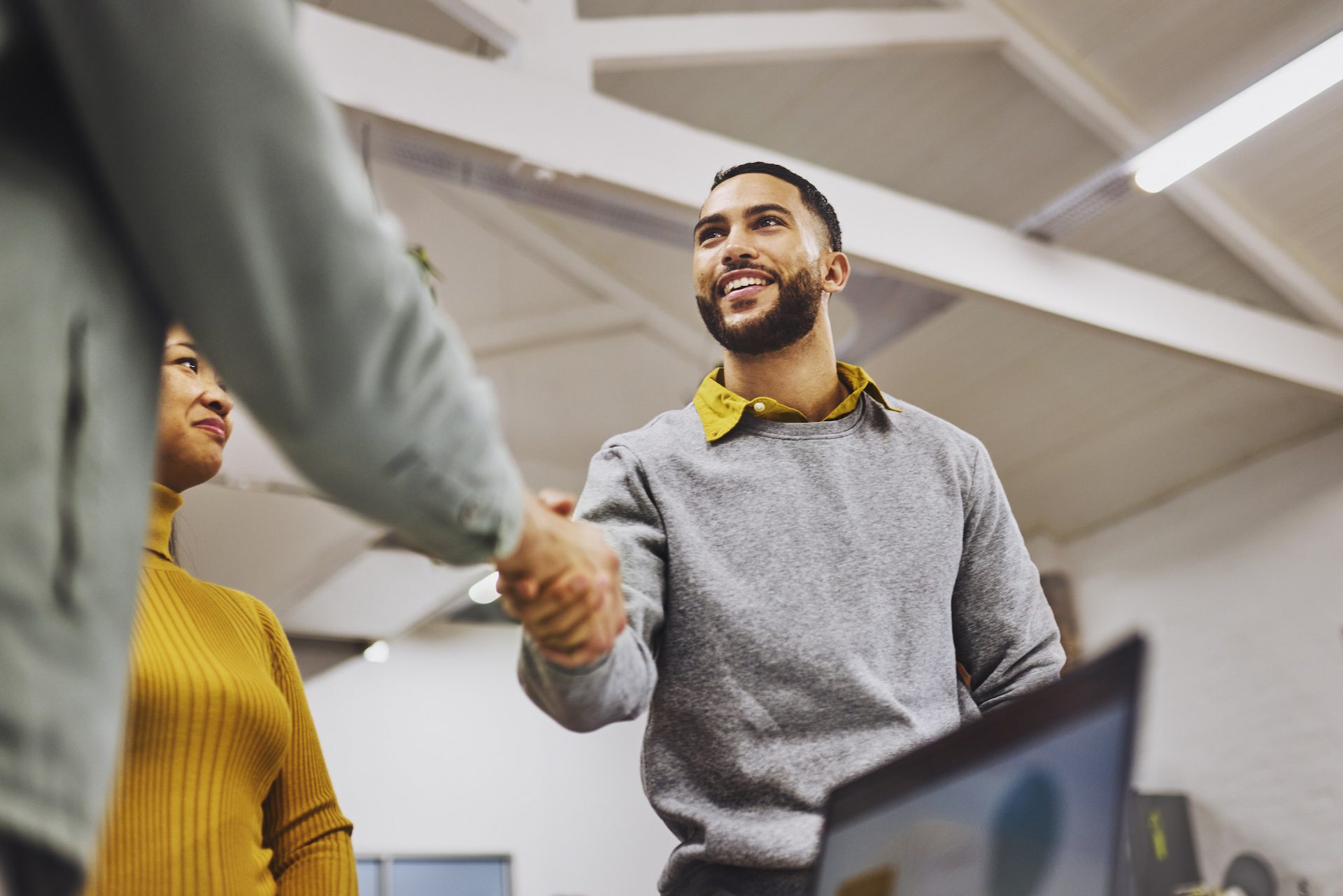 Low angle view of cheerful executive shaking hands with colleague in office.