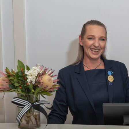 Woman smiling and standing behind a counter.