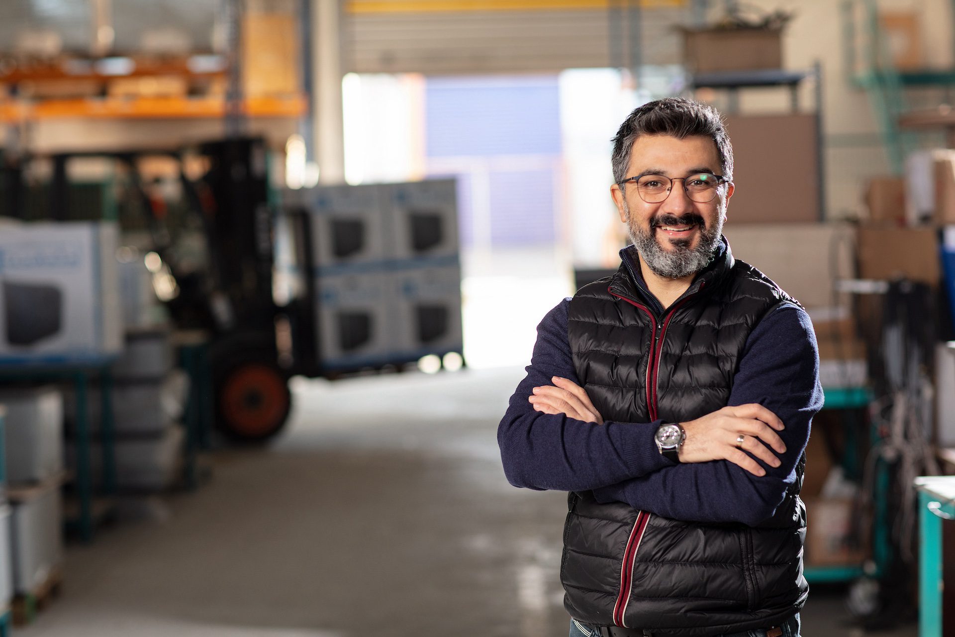 Profile of a man with arms crossed, standing in a warehouse.