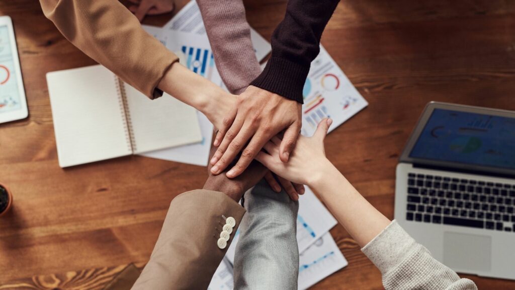 Top view of colleagues joining hands, symbolizing teamwork.