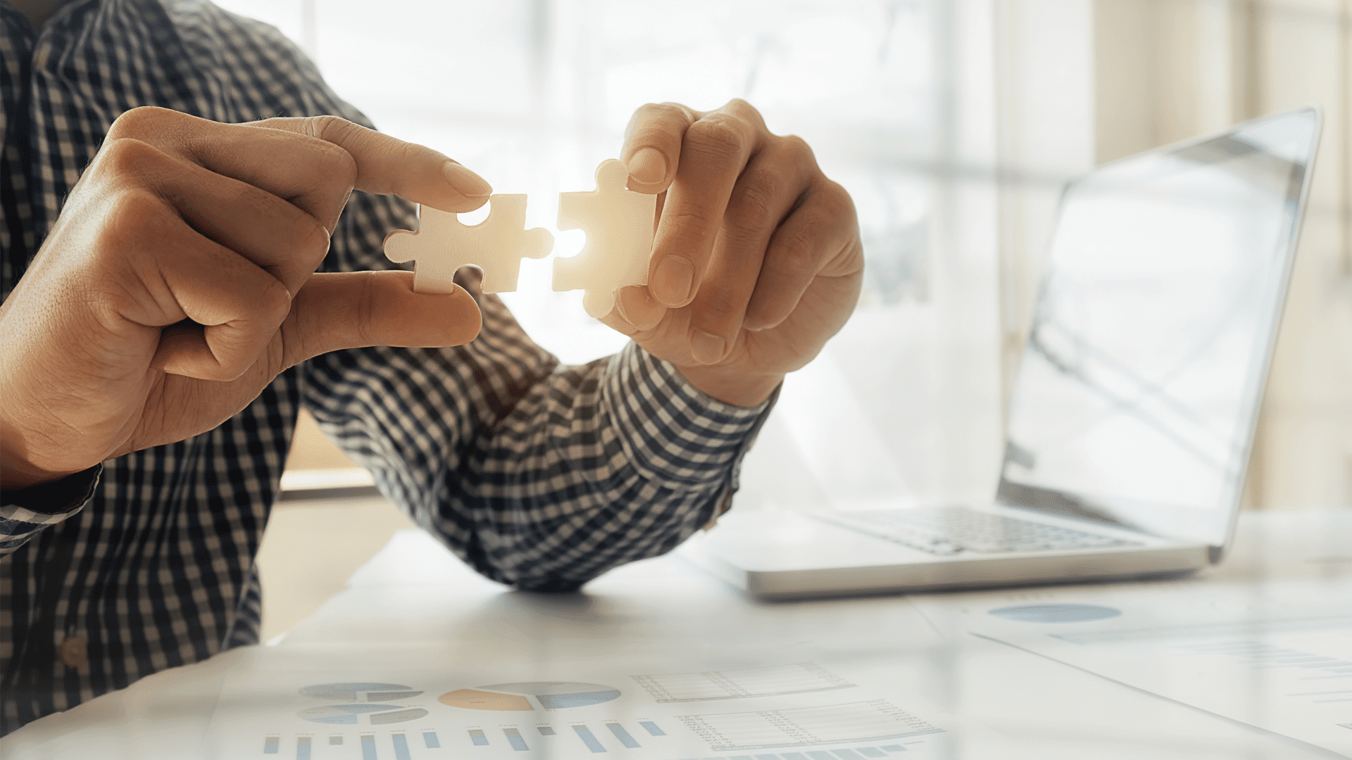 Focus on two hands holding jigsaw puzzle pieces that fit together.