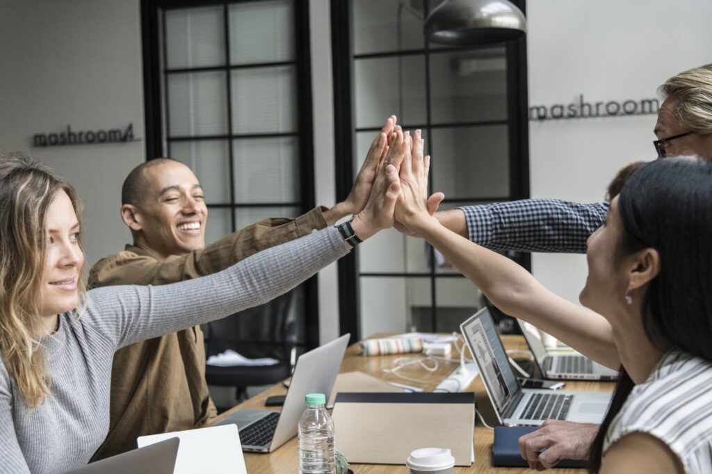 Young people around a table, high-fiveing each other