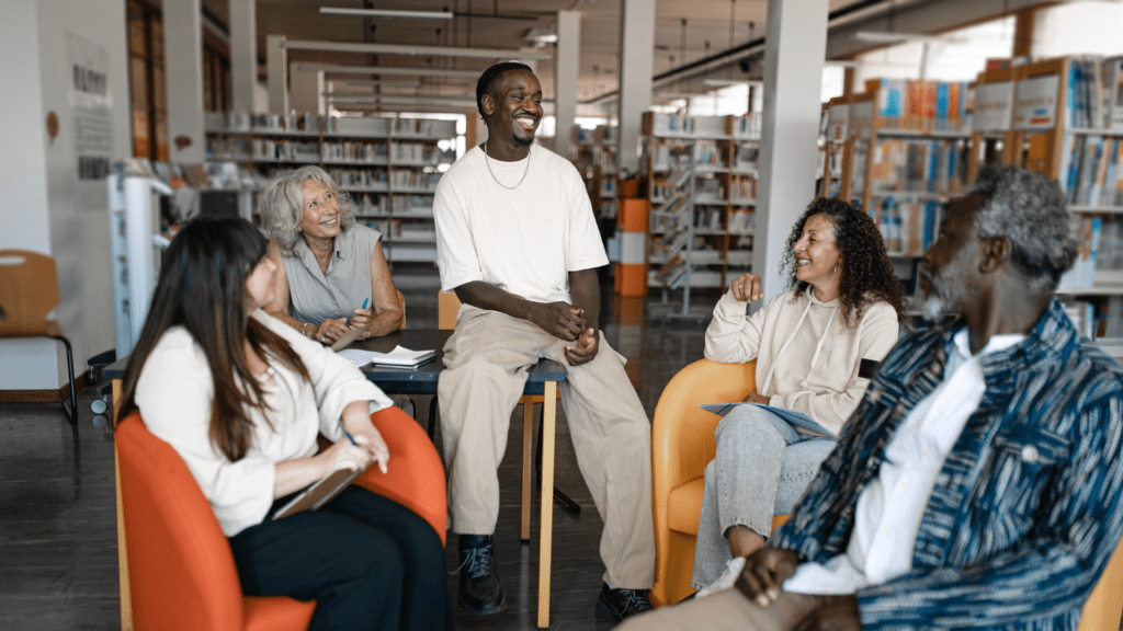 A group of racially diverse people sitting in a group in a library.