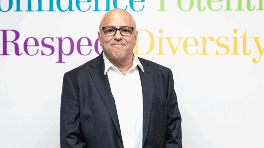 Man with glasses standing in front of a banner
