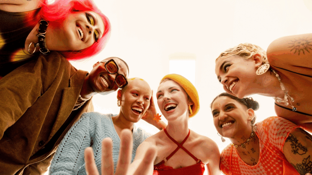 Diverse group of young adults smiling as they huddle together in a close circle