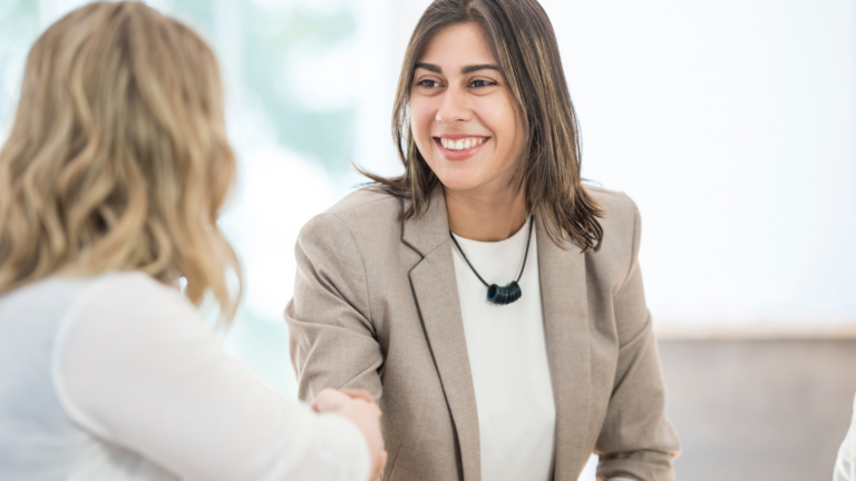 Two people shaking hands during a meeting about recruitment and employment support