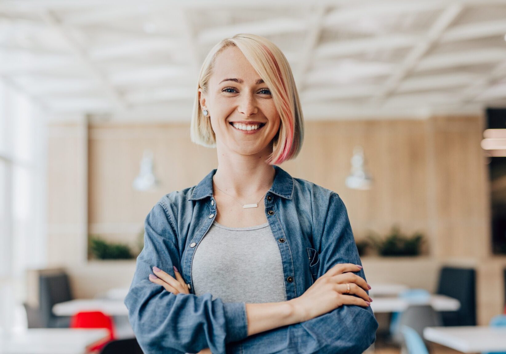 Smiling young blonde woman with a pink streak of hair.